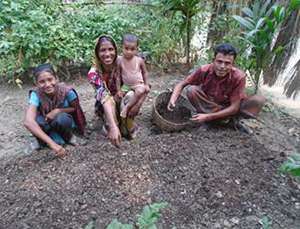Photo of Nasima and three members of her family in a vegetable garden.
