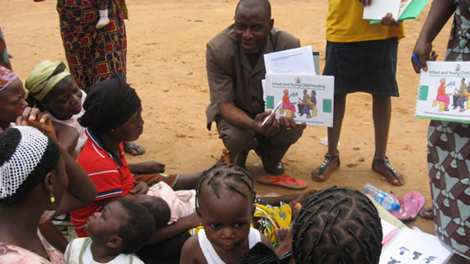 Photo of a man showing several people illustrated materials.