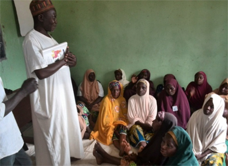 Photo of a man speaking to several seated women.