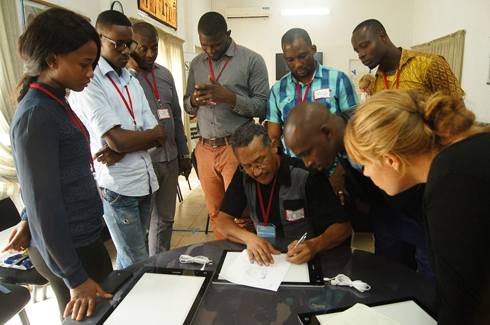 Participants look on as lead trainer Victor Nolasco demonstrates line drawing using a light table.