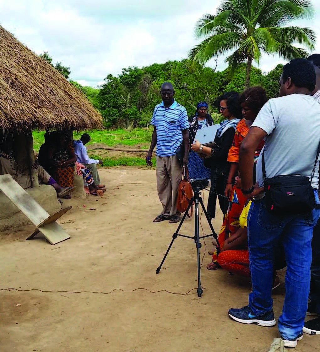 Photo of a group of women and men, standing outside a home, working on a video.
