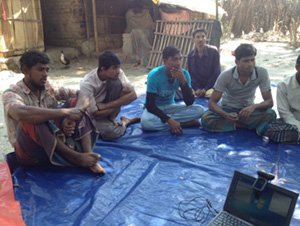 Photo of several men seated outside on a tarp. Phultala focus group discussion (Photo by T. Schaetzel)