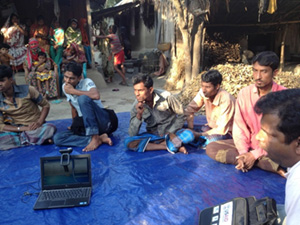 Photo of several men seated outside on a tarp. Rupsa focus group discussion (Photo by T. Schaetzel)
