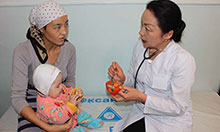 A doctor counsels a woman holding a baby on proper nutrition