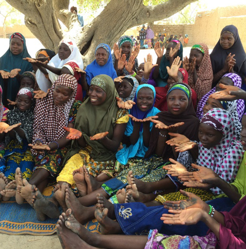 Photo of several women meeting outside with their hands outstretched