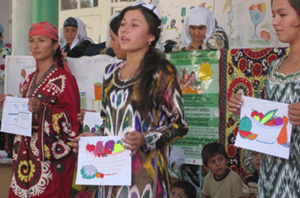 Photo of women speaking and holding diagrams and paintings of bowls of fruit.