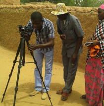 Photo of three people working a video camera on a tripod