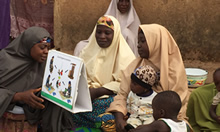 Young children accompanied their mothers while they listened to Mrs. Maryam Adams, a C-IYCF Community Volunteer in Kasuwan Magani ward in Kajuru LGA, discuss complementary feeding. C-IYCF Community Volunteers were observed to ask support group participants to explain the illustrations to ensure that they understood the messages.