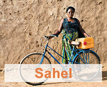 A woman stands with her bicycle in the Sahel.