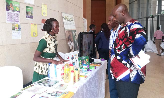Jennifer Akello (R), a SPRING/Uganda staff, explains to Members of Parliament about SPRING/Uganda’s work in the prevention and control of anemia and stunting through policy influence, food fortification and distribution of vitamin and mineral powders. This was during the inaugural Uganda Parliamentary Forum on Nutrition. 