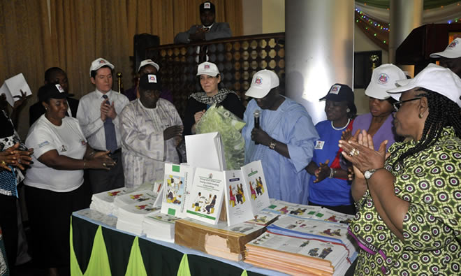 The Permanent Secretary of the Nigerian Federal Ministry of Health, his Excellency Ambassador Bala Sani (in blue), alongside the SPRING Nigeria team, looks over the package of resource materials on IYCF.