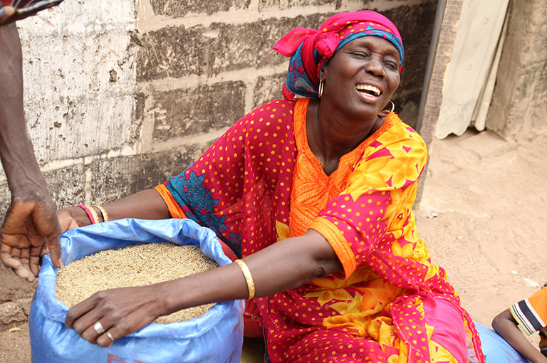 Photo of a woman holding a bag of grain.