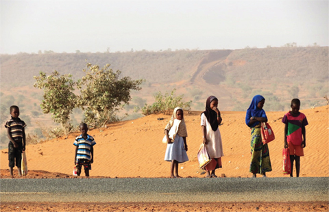 Photo of several children waiting along a road.