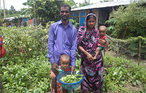 Piyara Begum and her family in her garden with harvested vegetables for consumption.