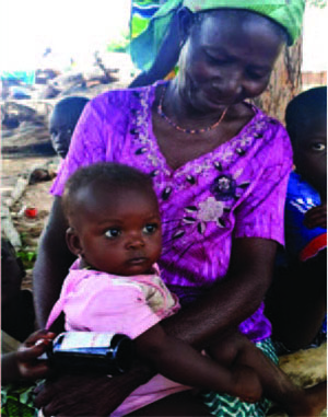 Photo of an older woman carrying a child on her lap, caption: Memunatu cares for her granddaughter, who now has a clean play space.