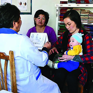 Photo of a young mother receiving instructions from </p>
<p>a health care worker with help from counseling cards. 
