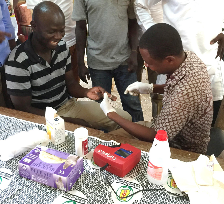 Photo of a man having his finger pricked by a health practitioner. 