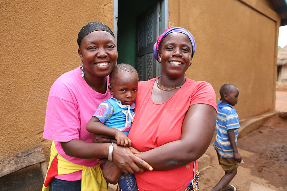 Sylla, a local community radio personality, poses with a mother and her child in Nialia.  