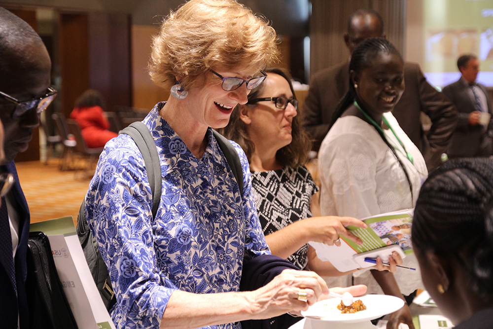 USAID Senegal Mission director Lisa Franchett tastes a meal made from the nutritious crops that SPRING/ Senegal promoted.