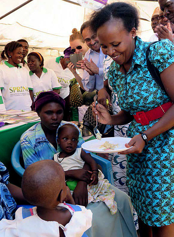 Guest of Honor Dr. Jacent Assimwe demonstrates how to feed a child with the food mixed with MNPs