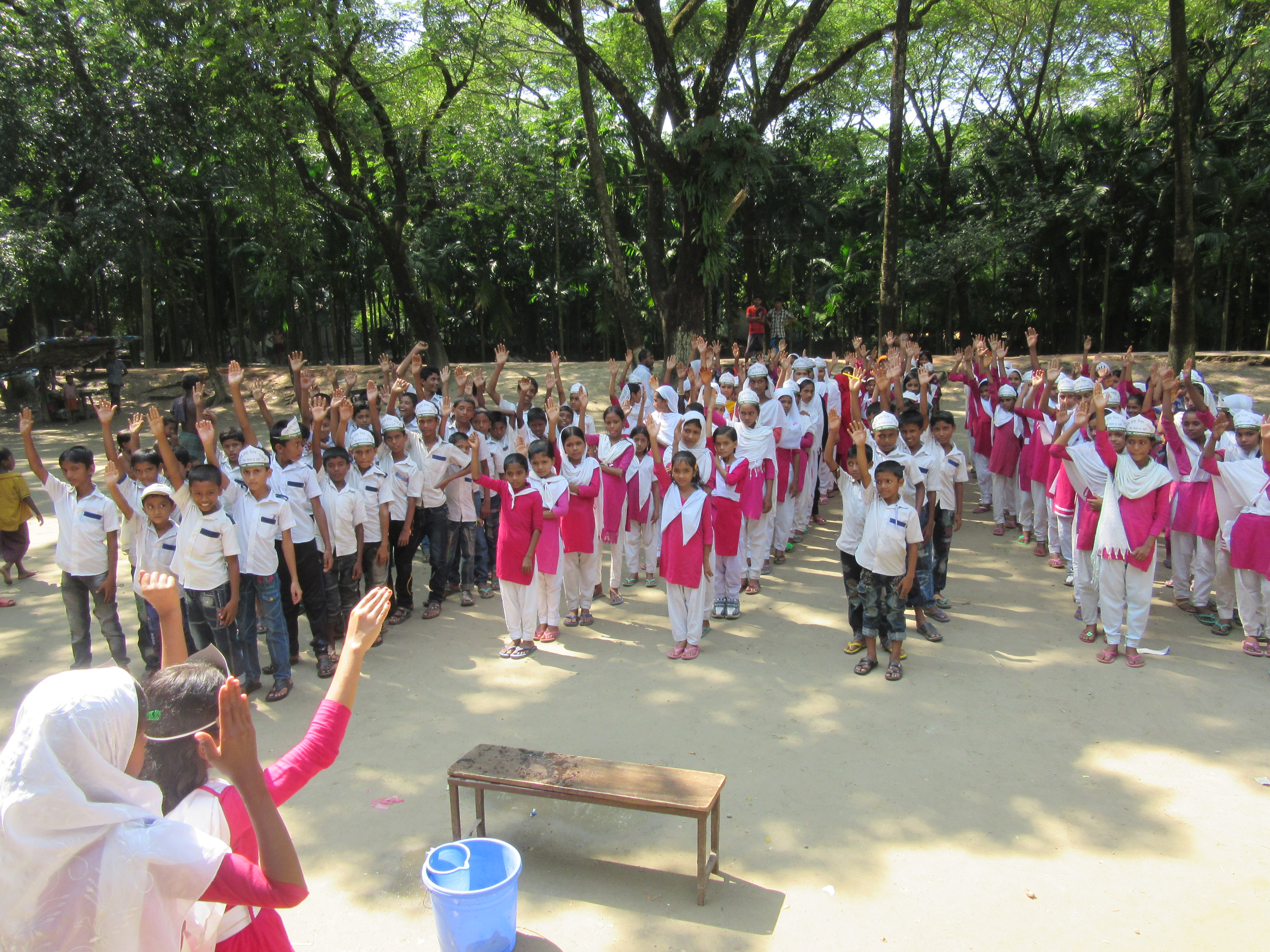 Several lines of children with hands up responding to their teacher