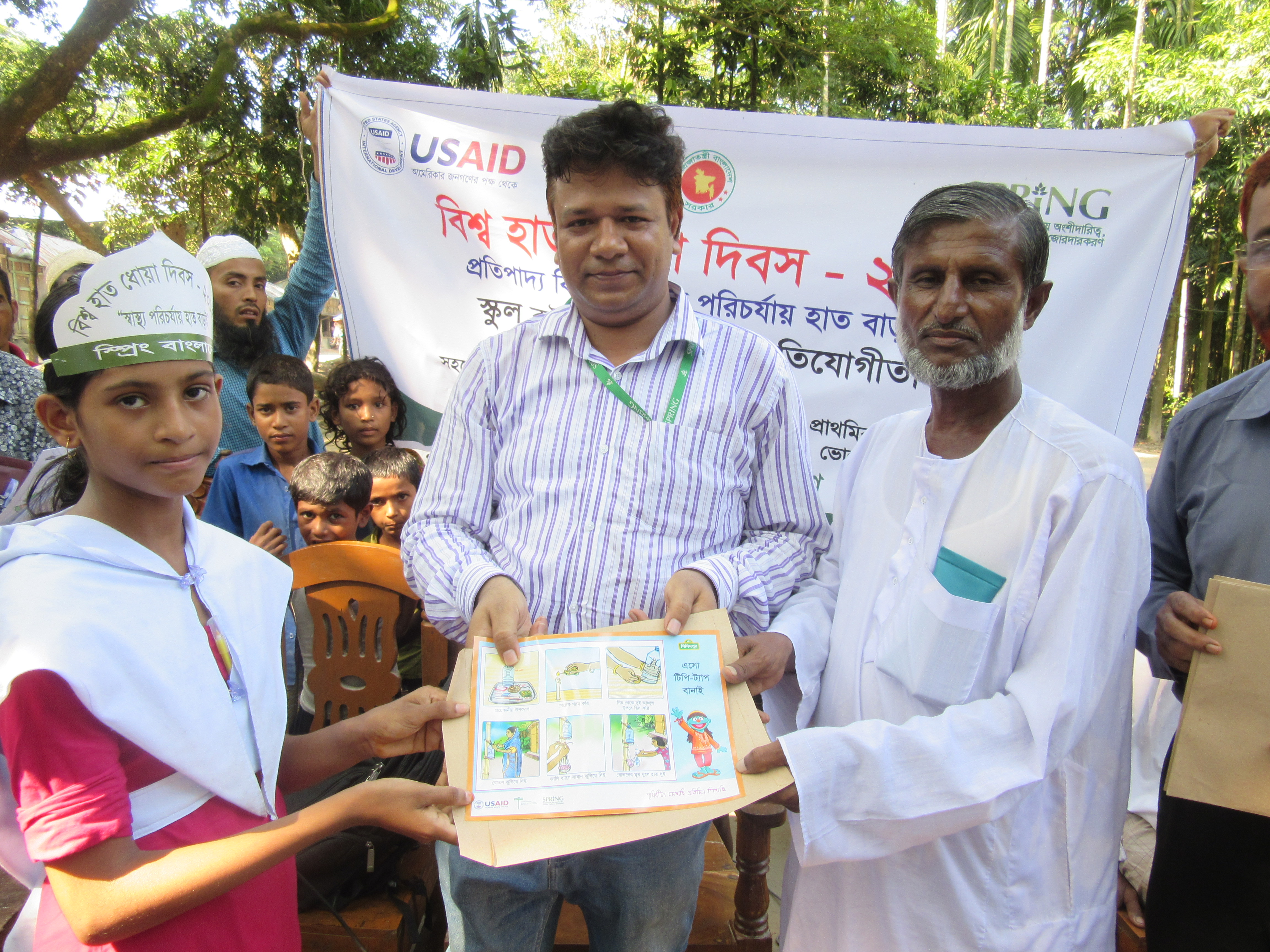 Two men and a woman displaying some children's coloring for Global Handwashing Day