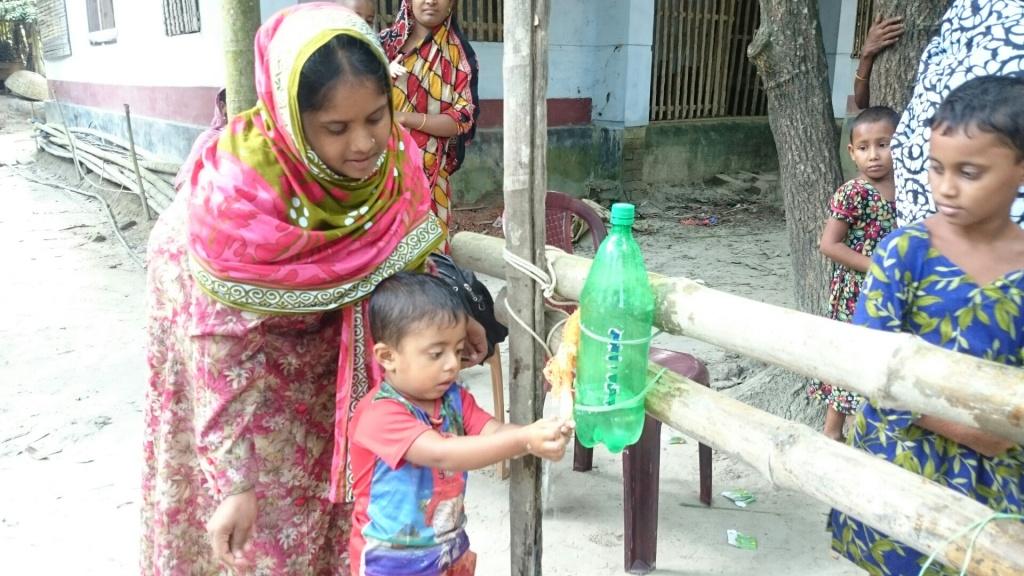 A woman and young child using a tippy tap