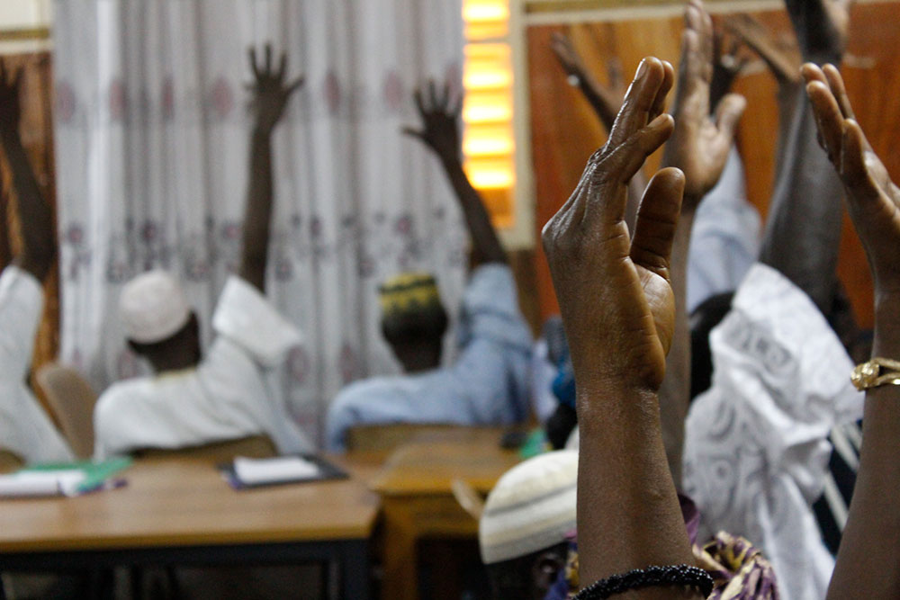 Participants raise their hands in agreement as part of a pre-training assessment on knowledge of gender concepts.