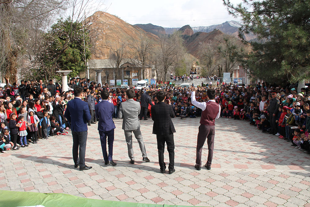 A singing group stands outside in a courtyard facing the large crowd wrapping around them.