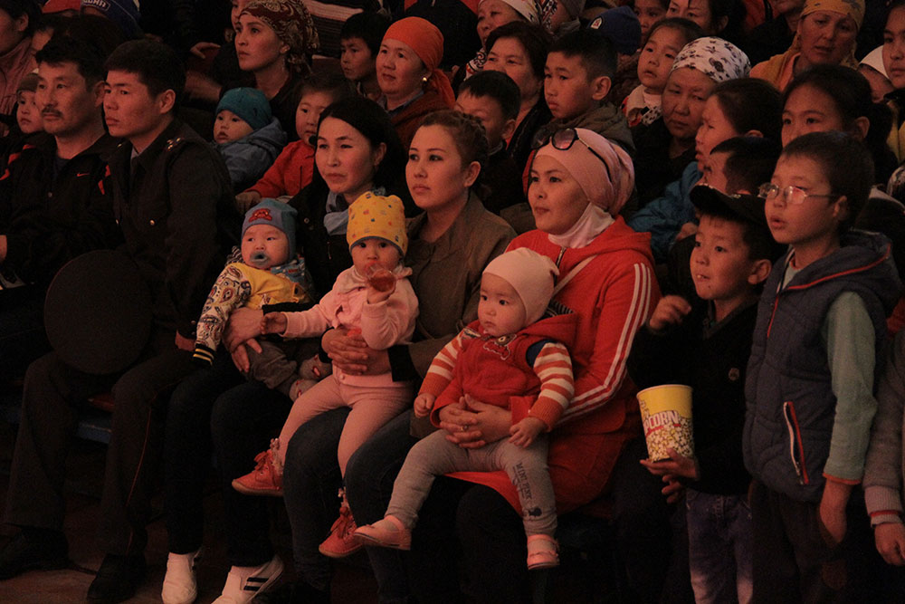 Concertgoers including a few babies sit in rapt attention during a concert.