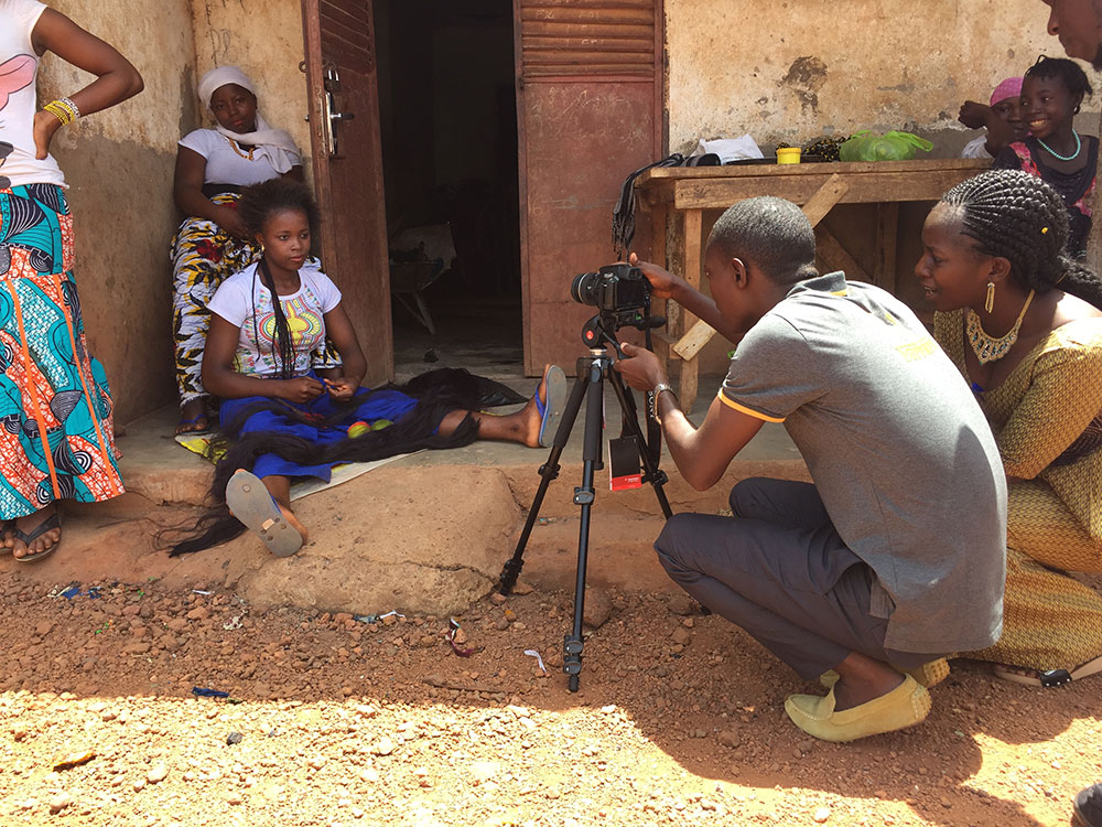 In April 2017, a new hub was formed in Mamou to serve partner projects in the central region of Guinea. These hubs were trained in the technical and creative processes of video production. Here, two training recipients, Millimouno and Jeannette, practice handling the video camera.