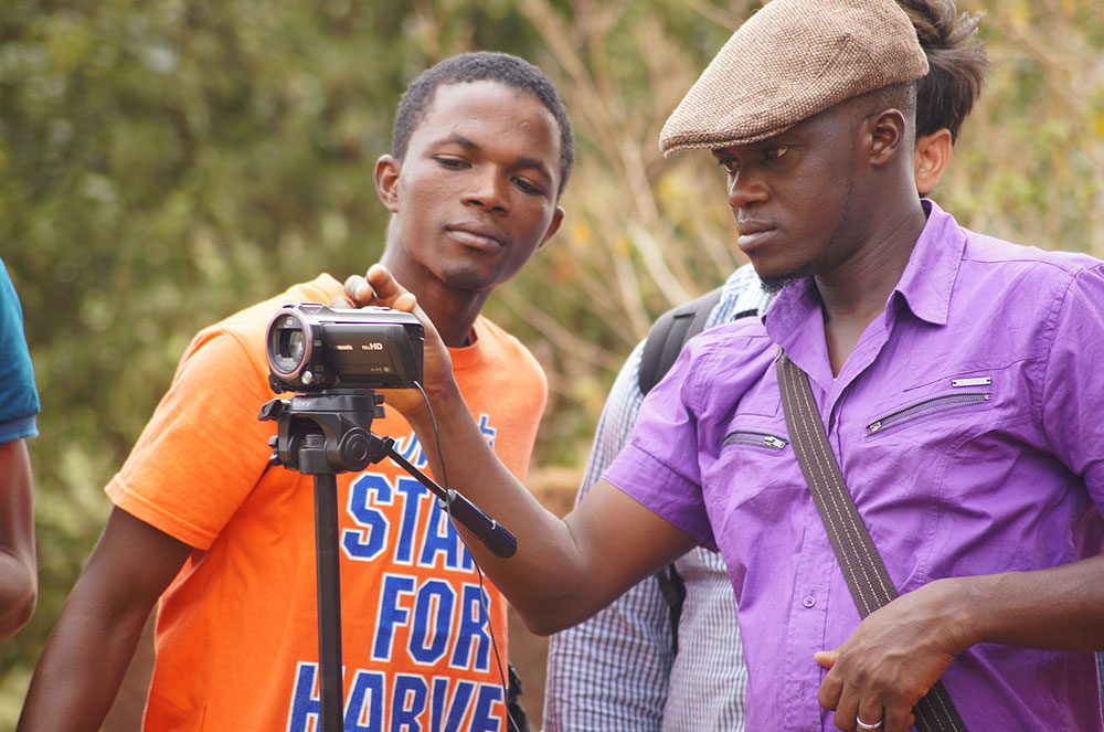 Mamadou Bhoye Sacko and Boubacar Barry observe the framing of their shot as they practice filming a video to show how to properly wash hands.