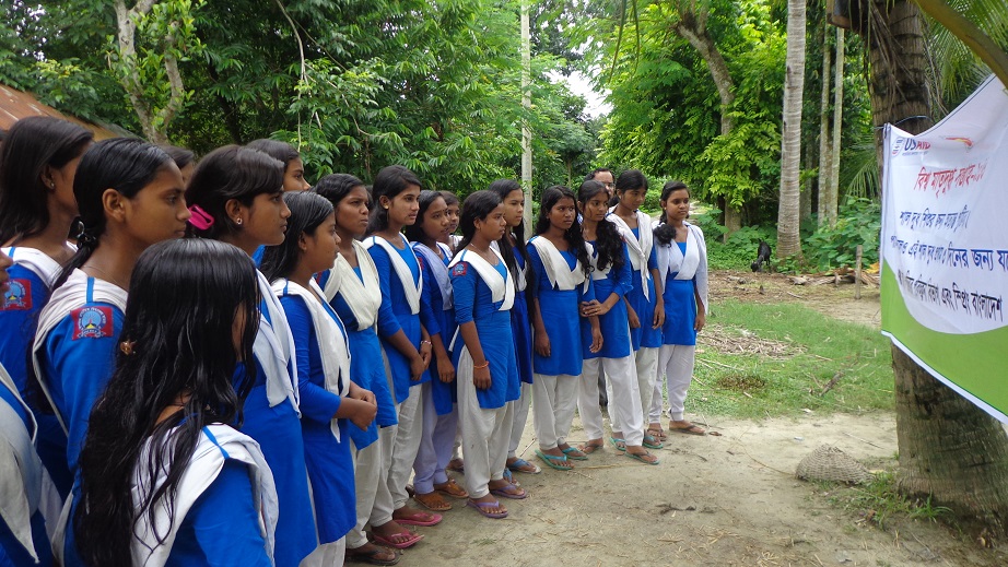 Girls read a roadside banner in Magura district about World Breastfeeding Week