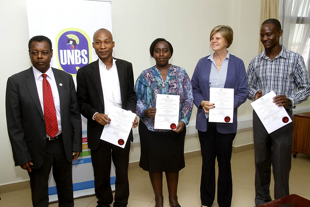 During a laboratory recognition ceremony, representatives of accredited laboratories pose with their certificates of recognition with Ben Manyindo (far left), the executive director of UNBS. With support of SPRING/Uganda, UNBS trained, assessed, and recognized five laboratories to help with the analysis of fortified foods.