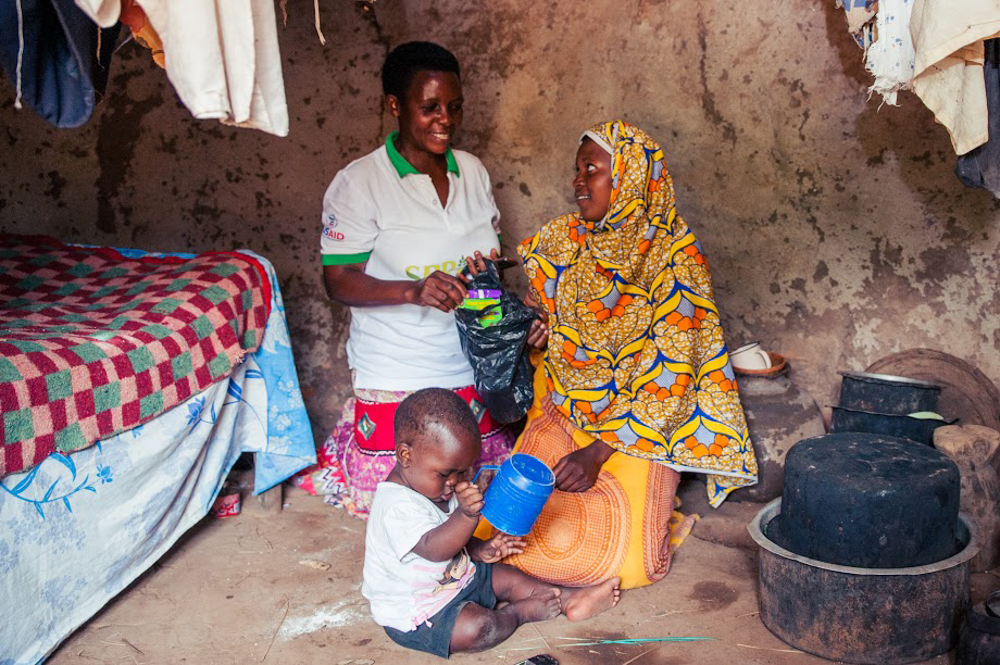 Muwolya, a VHT, shows the mother where to keep the MNP sachet in order for it to remain in good condition.