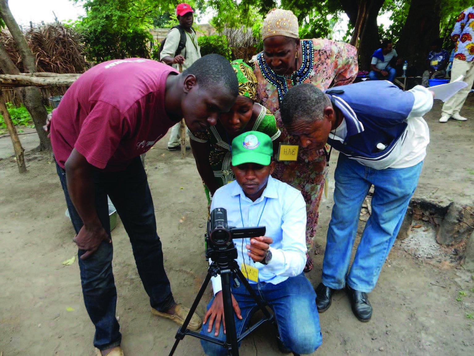 Photo of three men and two women looking at a camcorder as they work on a video. Caption: "SPRING/Guinea is adapting and testing the community video approach to promote nutritionspecific behaviors and nutrition-sensitive agriculture practices. For more on our work in Guinea, please visit: www.spring-nutrition.org/countries/guinea."