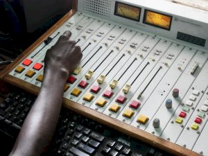 Photo is a closeup of hand at a set of audio controls