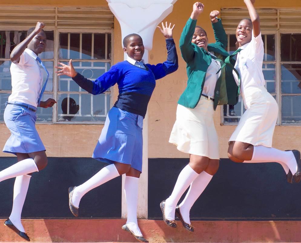 Cover photo: four teenage girls in their school uniforms, dancing and jumping as they pose for the camera. 