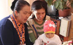 Nurse Usupova Mairam (on the left) counsels Jazgul about the best way to feed her one-year-old daughter Aitunuk.