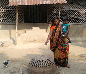 Dolly Mallick uses her new home food production skills to tend the chickens that provide eggs for her family. Photo credit: SPRING/Bangladesh