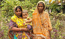 Woman holding child standing with mother-in-law outside