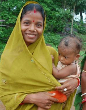 Photo of a young mother, standing and holding her child. Caption: "By selecting a model from the community, the team doesn't have to guess at appropriate cultural details and style of dress."