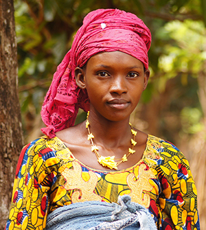 Photo of a young woman posing outside. Caption: "This shot in Guinea was taken in the afternoon under light cloud cover, giving us bright color while avoiding harsh shadows."