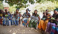 Photo of a group of women sitting on chairs under a tree.