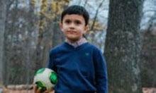 Carrie Malgarejo's son. He is posing in the woods holding a soccer ball.
