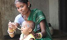 Woman spoon feeding a baby.