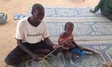 Man and child sit on a mat in Niger