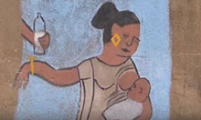 A chalk drawing on a wall of a mother breastfeeding her infant and pushing away someone's hand holding a bottle of milk.