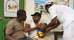 Health worker shows a mother proper breastfeeding techiques while the father looks on